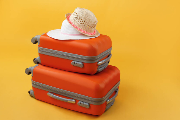コピースペースと黄色の背景に旅行バッグやわら帽子の2つの横にスーツケース。夏時間、休暇、観光の概念. - 写真・画像