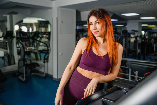 Portrait of sportive fit woman in gym interior, beautiful healthy female posing at modern sports hall with equipment - Photo, Image