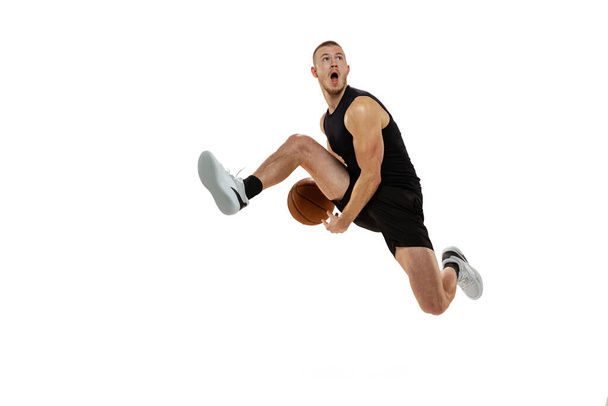 Dynamisches Porträt eines Basketballspielers, der mit Ball auf weißem Studiohintergrund springt. Sport, Bewegung, Bewegungskonzepte. Dunk, Marmelade, Zeug - Foto, Bild