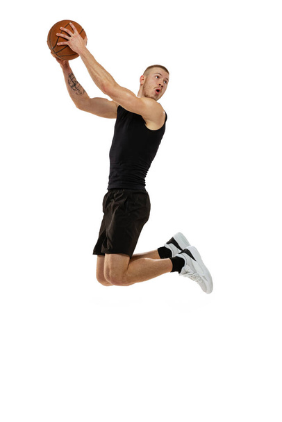 Streetball. Dynamic portrait of basketball player jumping with ball isolated on white studio background. Sport, motion, activity concepts. Dunk, jam, stuff technic - Photo, Image