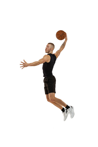 Flying. Portrait of basketball player jumping with ball isolated on white studio background. Sport, motion, activity concepts. Dunk, jam, stuff technic - 写真・画像