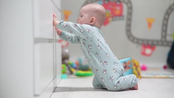 Een kruipende grappige baby thuis spelen met speelgoed. Baby jongen spelen met speelgoed binnen thuis. - Video