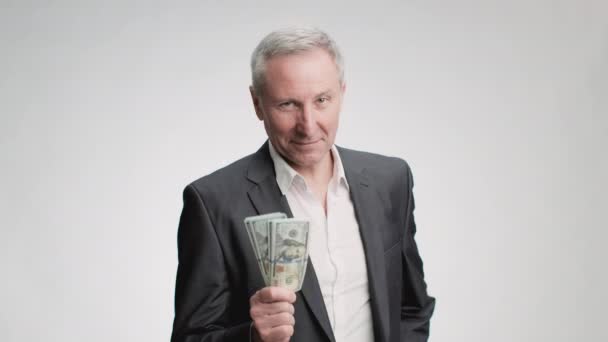 Jubilación exitosa y riqueza. Rico confiado hombre mayor usando traje mostrando pila de dinero a la cámara y sonriendo - Metraje, vídeo