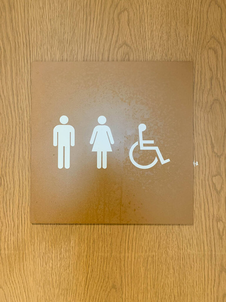 Señal de hombre, mujer e inhabilitar el baño en la puerta de madera - Foto, imagen