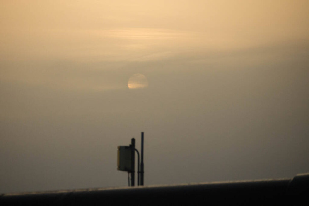 背景にある月を背景に空港の日の出の屋根の上の技術装置の感動的なイメージ  - 写真・画像