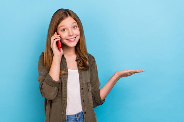 Photo of beautiful positive girl talk phone hold hand promote product object isolated on blue color background - Valokuva, kuva