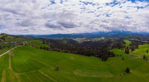 View from above on beautiful green meadows, snow-capped peaks of the Tatra Mountains in the distance. View from the air. View from the drone. - Foto, Imagem