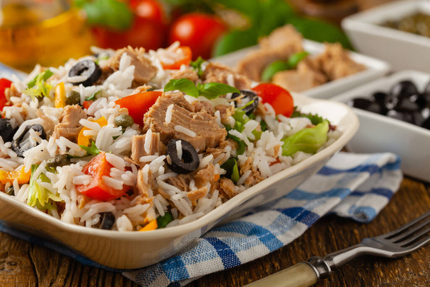 Italian tuna salad with rice, olives and capers. Front view. Natural wooden background. - Foto, immagini