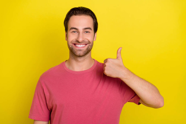 Photo of reliable promoter guy raise thumb up approve choice wear pink t-shirt isolated yellow color background - Foto, Imagen