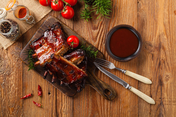 Roasted pork ribs in a bbq sauce. Served on a wooden board. Top view. - Fotografie, Obrázek