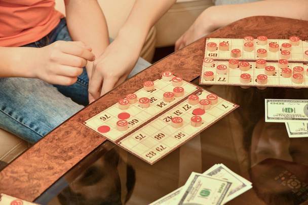 Картки лото, чіпси і гроші лежать на скляному кавовому столі. Люди грають лотерею за гроші
. - Фото, зображення