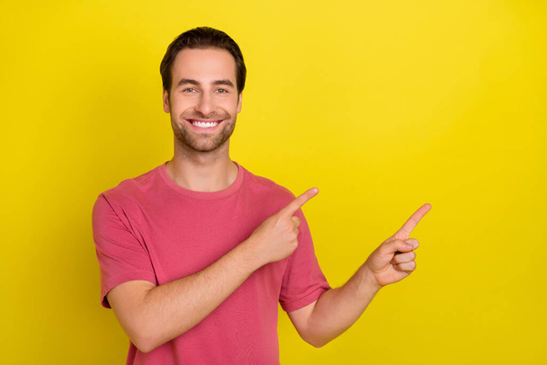 Photo of confident cheerful guy direct finger empty space novelty wear pink t-shirt isolated yellow color background - Valokuva, kuva