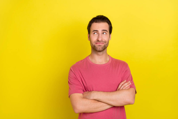 Photo of minded pensive interested guy crossed arms look empty space wear pink t-shirt isolated yellow color background - Foto, afbeelding