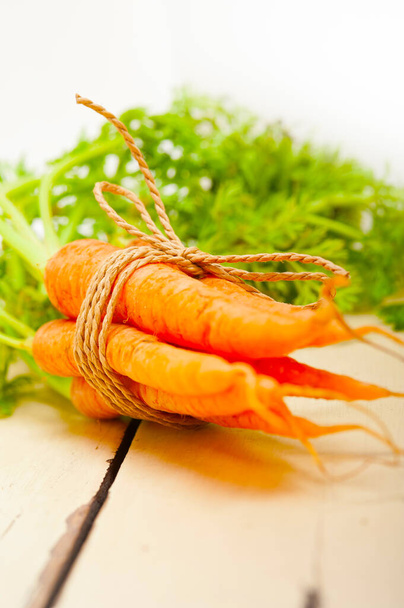 frische Baby-Karotten mit Seil auf rustikalem Tisch gebunden - Foto, Bild
