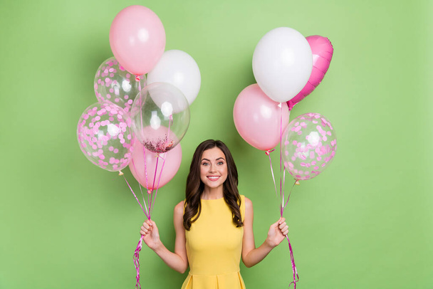 Portrait of attractive cheerful girly wavy-haired girl holding air balls occasion isolated over bright green color background - Fotó, kép