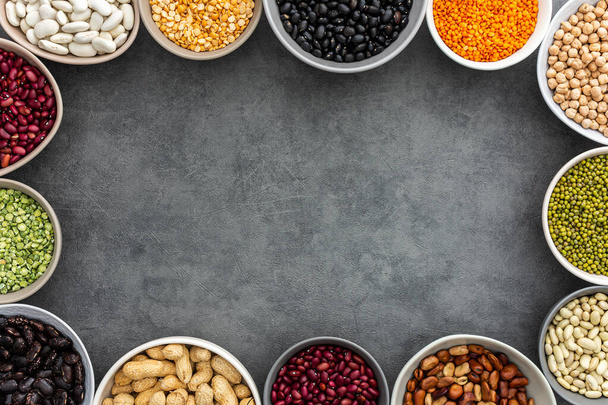 Frame of various types of legumes in bowls, green and yellow peas, chickpeas and peanuts, colored beans and lentils, mung beans and beans, top view, copy space - Photo, Image