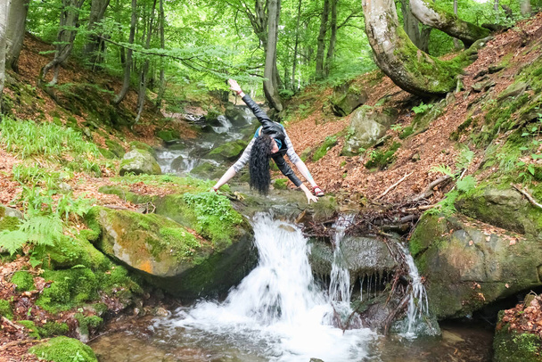 брюнетка, демонстрирующая позу йоги в летнем лесу у ручья, Украинские Карпаты, наружная жизнь - Фото, изображение