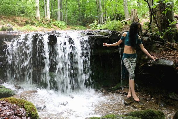 Esmer kadın dağ şelalesinin yanında poz veriyor, Karpatya ormanı, yaz tatili. - Fotoğraf, Görsel