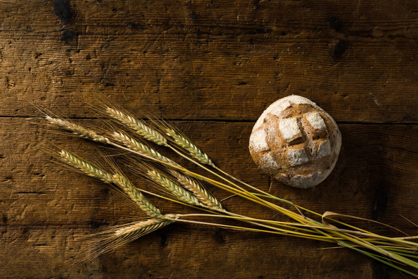 pane fatto in casa con spighe di grano sul tavolo di legno - Foto, immagini