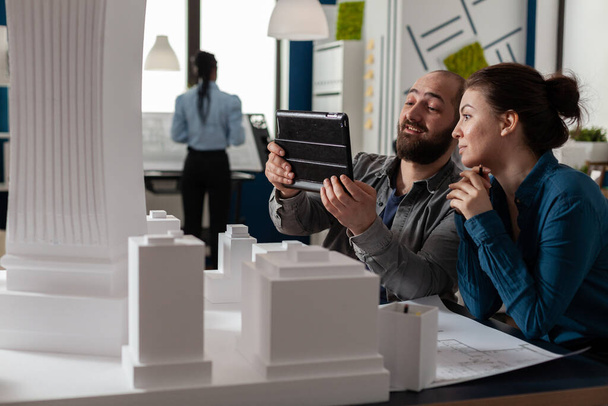 Dos arquitectos trabajando juntos mirando tableta con planos - Foto, Imagen