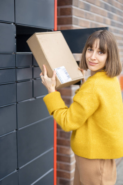 Žena, která dostává balík z buňky automatického poštovního terminálu venku - Fotografie, Obrázek