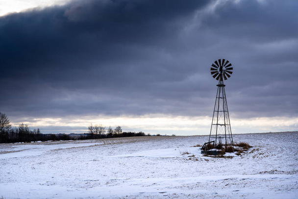 ロッキービュー郡のカナダの草原の雪に覆われたフィールドの古い風車アルバータ州 - 写真・画像