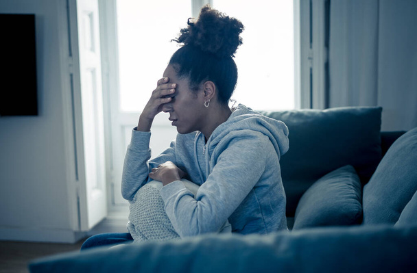 Przygnębiona młoda, atrakcyjna Afroamerykanka leżąca na kanapie w domu, smutna, zmęczona i zmartwiona, cierpiąca na depresję, stres i niepokój w psychice, samotność i izolację.. - Zdjęcie, obraz