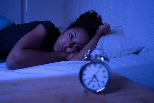 Young beautiful afro american woman at home lying in bed late at night trying to sleep suffering insomnia sleeping disorder or scared on nightmares looking stressed and worried Mental health concept. - Photo, image