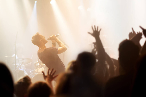 Вивертаючись. рок-зірка співає в його мікрофон, в той час як фанат витягує руки до нього
. - Фото, зображення