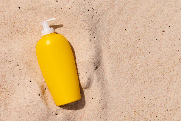 Tubo amarillo de crema solar en la arena. Concepto de protección UV y contra quemaduras solares. Burla.. - Foto, Imagen