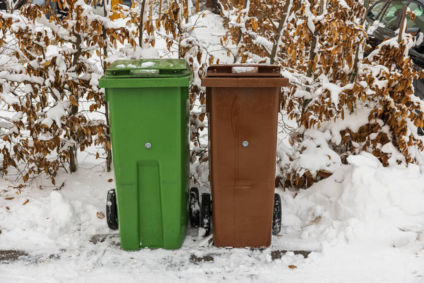 Close-up zicht op twee besneeuwde afvalsorteerbakken in de privétuin op ijzige winterdag. Zweden. - Foto, afbeelding