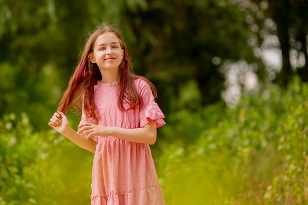 Girl 10 years old in a pink dress on a sunny summer day. Beautiful teen girl. - Photo, Image