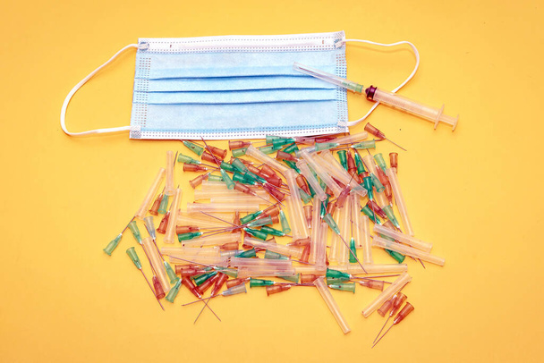 Pile of used needles toxic medical waste with injection syringe and surgical face mask - Φωτογραφία, εικόνα