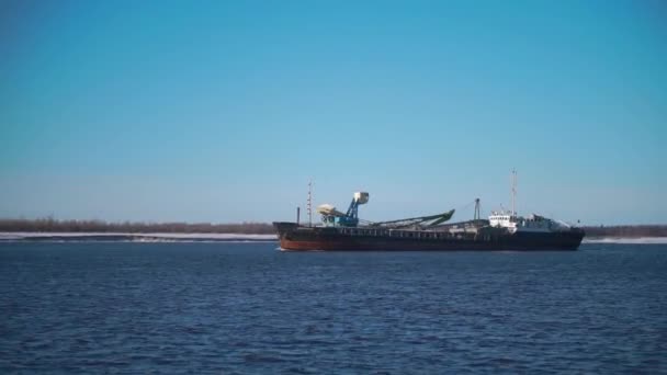 Cargo ship sailing on river on clear day. Clip. Merchant ship or barge sails along river. Commercial and industrial shipping - Footage, Video