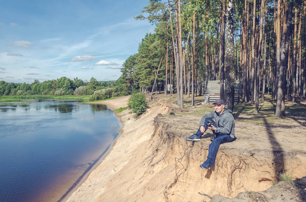 Photographer relaxes in nature near the river. Beautiful landscape outdoor recreation. - 写真・画像