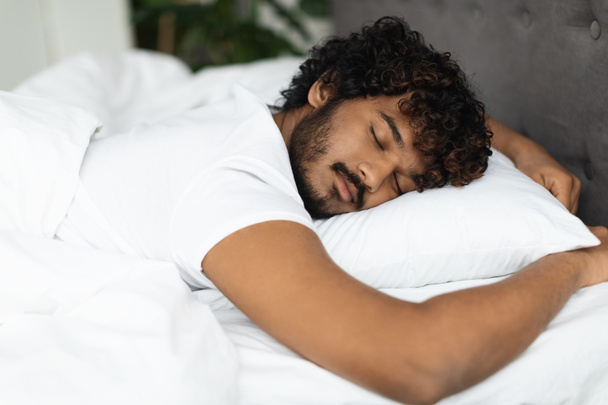 Nahaufnahme eines jungen indischen Mannes, der im Bett schläft - Foto, Bild