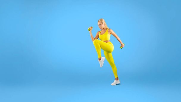 Young Woman Exercising With Dumbbells Isolated On Blue Background - Valokuva, kuva