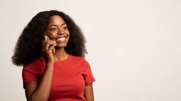 Un appel téléphonique. Gros plan de heureuse jeune dame noire parlant sur téléphone portable - Photo, image