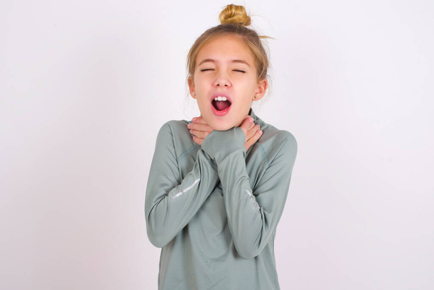little caucasian kid girl wearing sport clothing over white background shouting suffocate because painful strangle. Health problem. Asphyxiate and suicide concept. - Foto, imagen