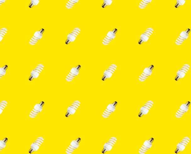 the concept of saving energy. seamless pattern of fluorescent lamps on a yellow background. - Foto, afbeelding
