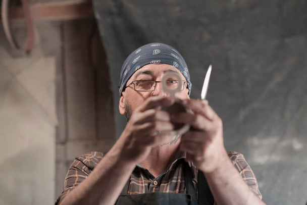 Spoon craft master in his workshop with handmade wooden products and tools working checking curve and line straight. High quality photo - Foto, Bild