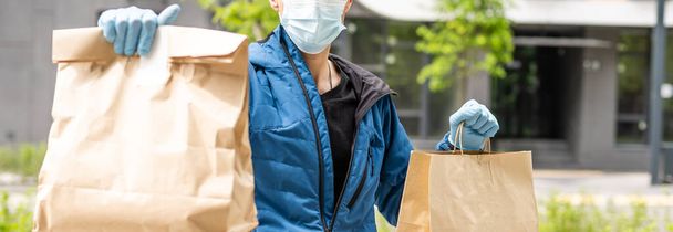 Giovane uomo di consegna ispanico con maschera facciale mentre trasporta pacchi durante l'epidemia di coronavirus. - Foto, immagini