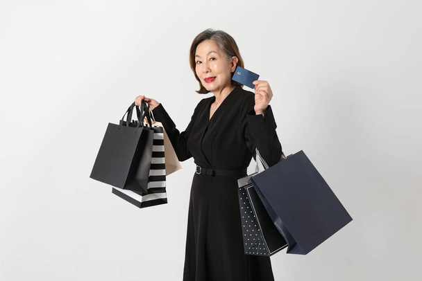 fashionable Asian Korean senior woman, holding a credit card and shopping bag - 写真・画像