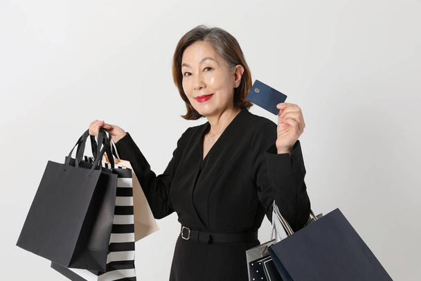fashionable Asian Korean senior woman, holding a credit card and shopping bag - Foto, immagini