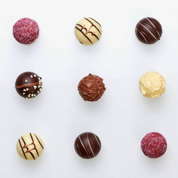 nove tartufi di cioccolato in tre file simmetriche su fondo bianco - Foto, immagini