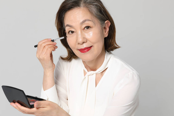Asian Korean senior woman, bold and red cosmetics makeup beauty concept in studio - Foto, afbeelding
