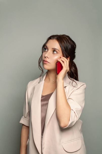 Poważna kobieta w garniturze telefon na szarym tle - Zdjęcie, obraz