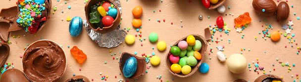 Tasty chocolate Easter eggs with different candies on beige background - Photo, Image