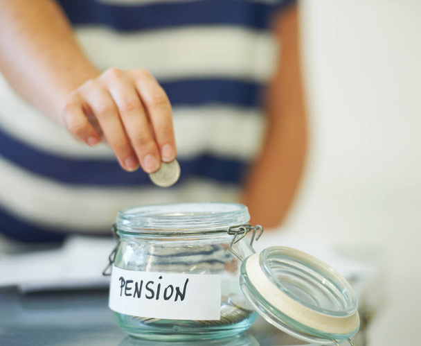 Saving penny for penny. A person putting a penny in a jar that is labeled amp039Pensionamp039. - Photo, Image