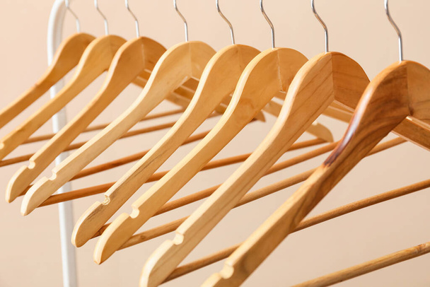 Rack with wooden clothes hangers on light background - Foto, imagen